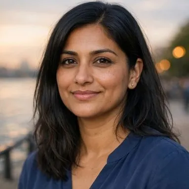 South Asian woman, late 30s, thick black hair, brown eyes, soft navy blouse, warm golde…